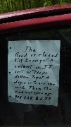 sign in window of car with destroyed tires blocking the road